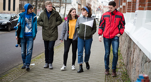 Eine Gruppe junger Menschen geht eine Strae entlang.