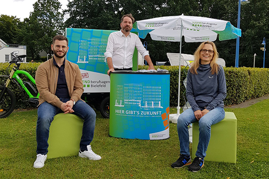 Drei Mitarbeitende an einem Informationsstand im Grnen